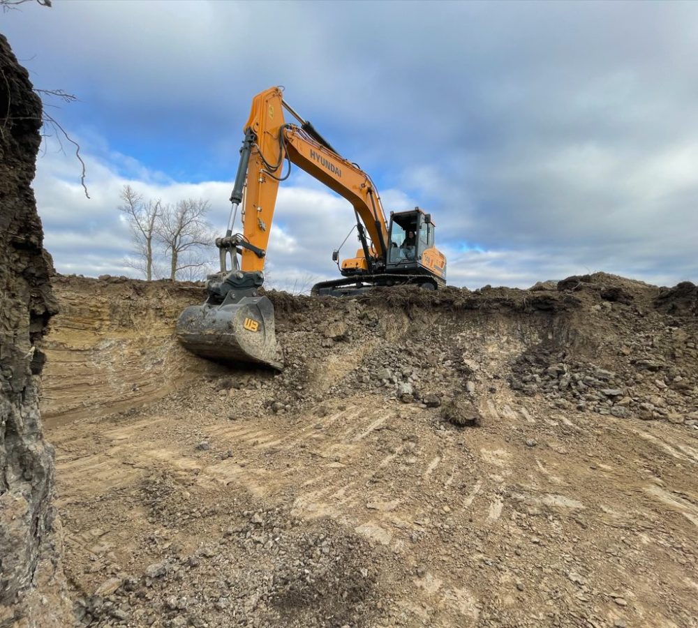 Excavator cutting into a hillside during a site excavation job