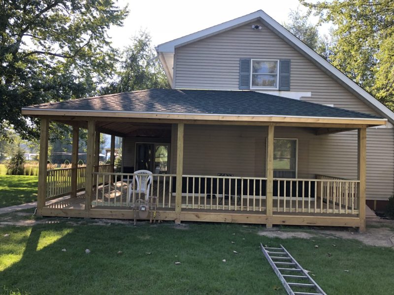 Completed covered porch addition with railing on a two-story home