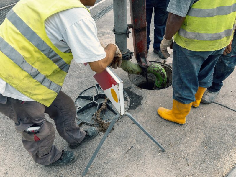 Crew servicing an underground tank access in a paved area