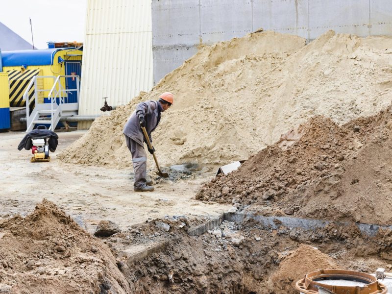 Worker shoveling in a deep excavation at a construction site