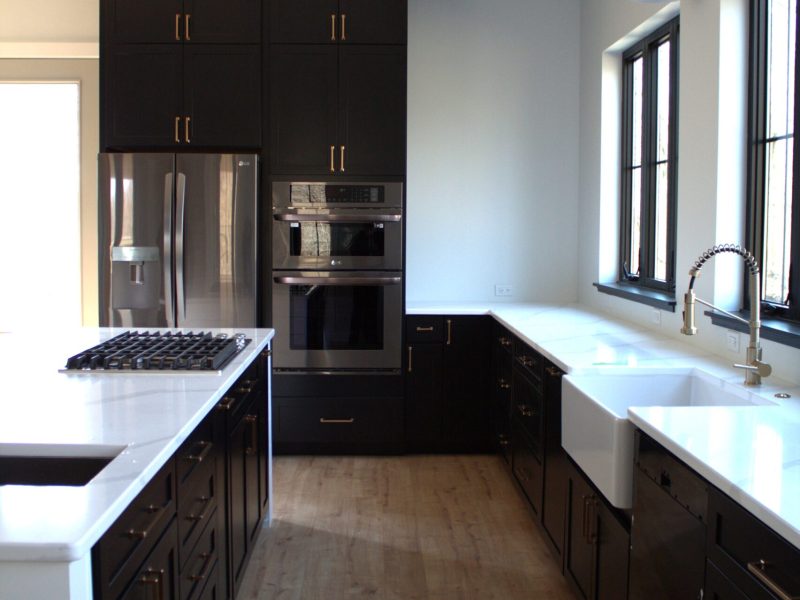 Custom kitchen with dark cabinets, double wall ovens and a farmhouse sink