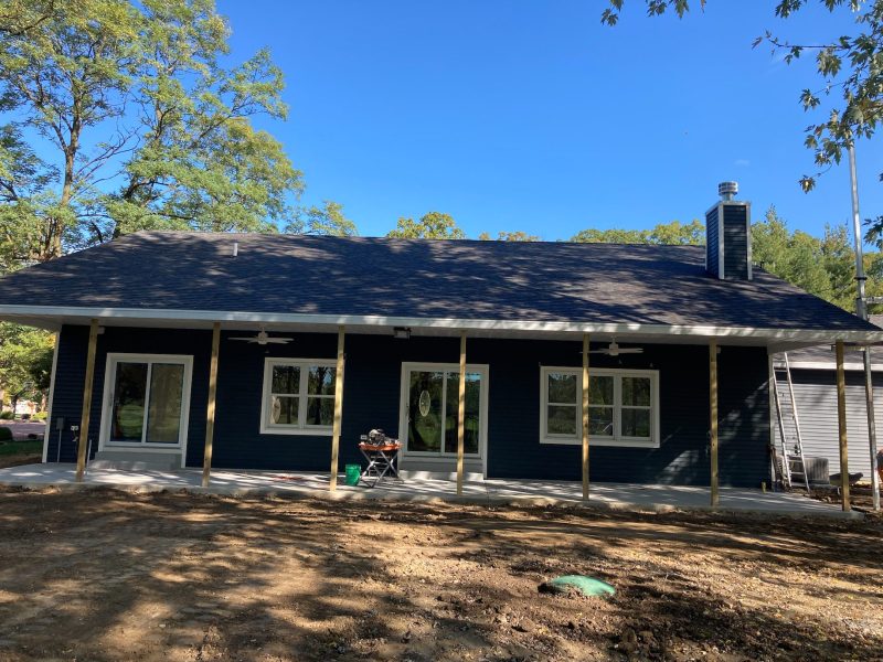 Navy lakefront cottage with a new roof and covered porch under construction
