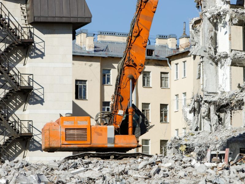 Long-reach excavator demolishing a multi-story masonry building
